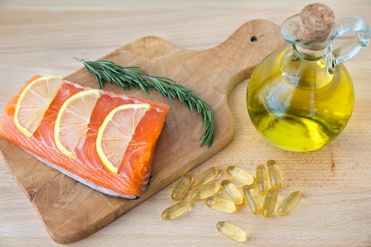 Fish oil capsules, cod liver, and salmon fillet on wooden surface