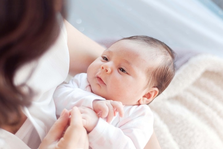 Mother with her newborn baby. Mother is holding her little baby girl.  Photo with the effect of sunlight, soft natural light, with selective focus.